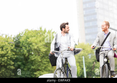 Geschäftsleute, die während der Fahrt Fahrräder im freien sprechen Stockfoto