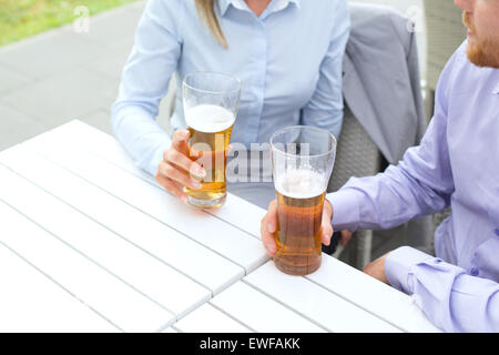 Mittelteil von Geschäft paar hält Biergläser im Restaurant unter freiem Himmel Stockfoto