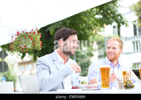 Glücklich Geschäftsleute, die mit Lebensmitteln in Straßencafé Stockfoto