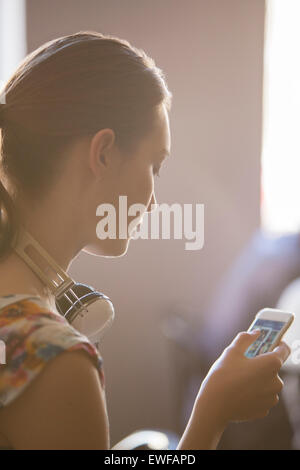 Frau mit Kopfhörern mit Handy, Nahaufnahme Stockfoto