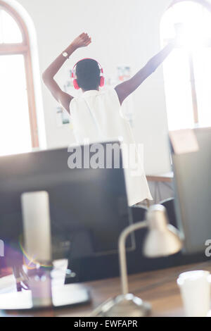 Lässige Geschäftsfrau mit Kopfhörern tanzen im Büro Stockfoto