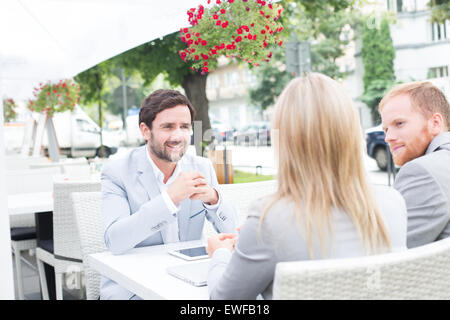 Glücklich Kaufmann mit Kollegen im Straßencafé zu diskutieren Stockfoto