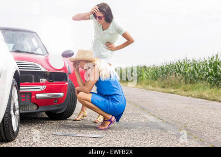 Gespannten Blick auf beschädigte Autos auf der Straße gegen Frauen klarer Himmel Stockfoto