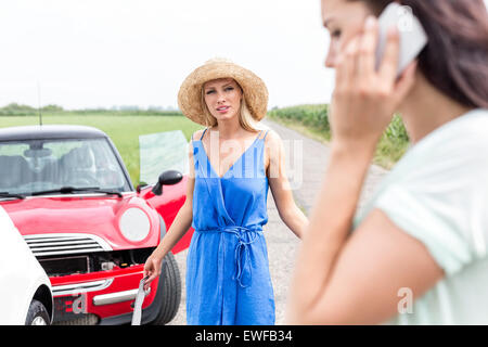 Böse Frau weiblich mit Handy von beschädigten Autos unterwegs betrachten Stockfoto