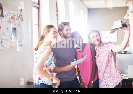 Kreative Geschäftsleute unter Selfie mit Sofortbild-Kamera im Büro Stockfoto