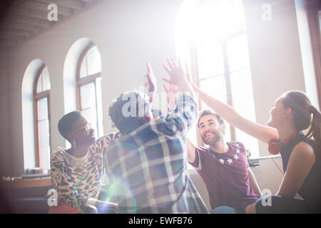 Casual Business-Leute, die Hände im Kreis im sonnigen Büro treffen Stockfoto