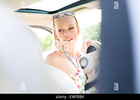 Schöne Frau, die während der Fahrt Auto im Rückblick Stockfoto