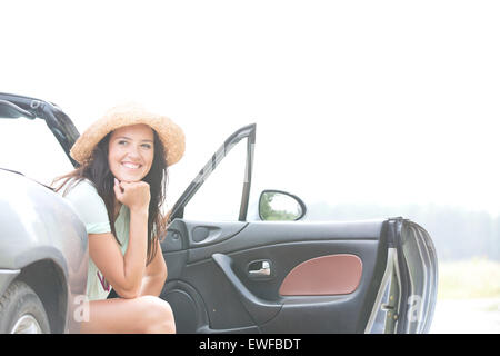 Glückliche Frau sitzen im Cabrio gegen klarer Himmel Stockfoto