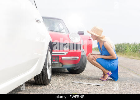 Full-length Seitenansicht des gespannten Frau betrachten beschädigte Autos unterwegs Stockfoto