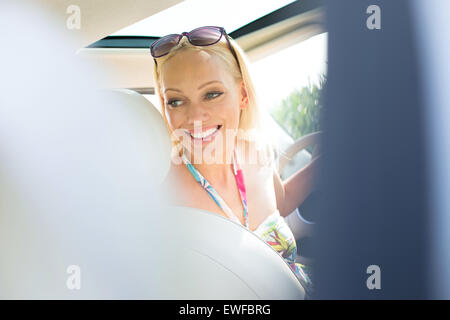 Happy Woman with Blick zurück, während Auto fahren Stockfoto