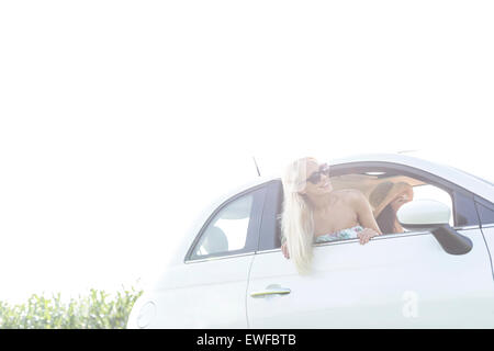 Glückliche Freundinnen genießen im Auto gegen klarer Himmel Stockfoto