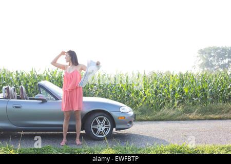 Voller Länge Frau Abschirmung Augen haltend Karte Cabrio Stockfoto