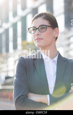 Nachdenklich Geschäftsfrau stehend Arme gekreuzt im freien Stockfoto
