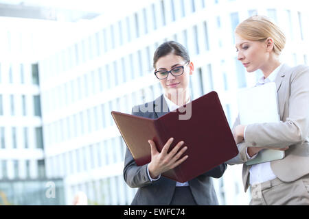 Geschäftsfrauen, die Ordner zu lesen, während außen Bürogebäude stehen Stockfoto