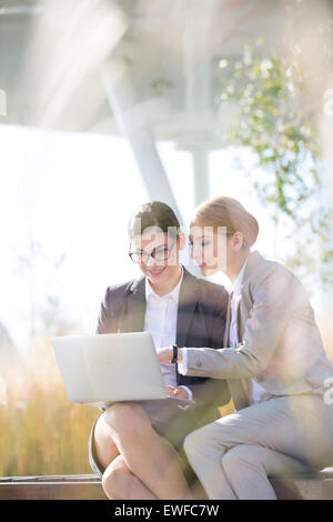 Glücklich Geschäftsfrauen mit Laptop zusammen an sonnigen Tag Stockfoto