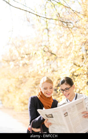 Glücklich Geschäftsfrauen lesen Zeitung zusammen im park Stockfoto