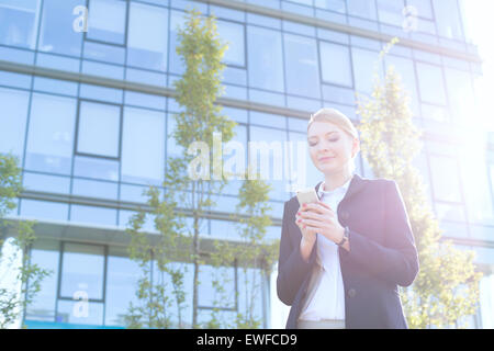 Geschäftsfrau SMS über Handy an sonnigen Tag Stockfoto
