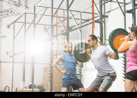 Menschen Sie unterstützen Mann bei der Aufhebung der Langhantel bei Crossfit gym Stockfoto