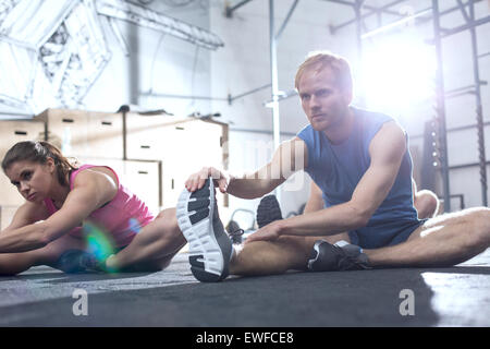 Zuversichtlich, dass Mann und Frau dabei dehnen im Crossfit Fitnessstudio trainieren Stockfoto