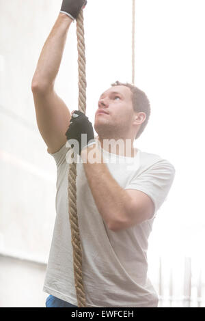Entschlossenen Mann Kletterseil in Crossfit gym Stockfoto