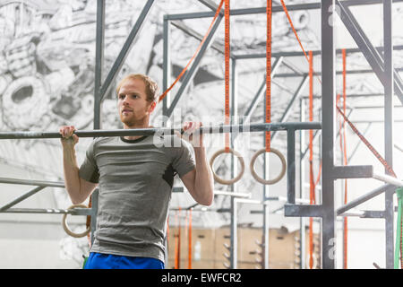 Zuversichtlich Mann tut Klimmzüge in Crossfit gym Stockfoto