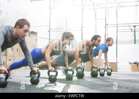 Engagierten Menschen tun Liegestütze mit Kettlebells bei Crossfit gym Stockfoto