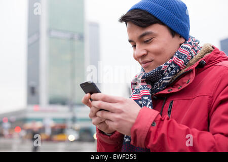 Lächelnder Mann mit Handy in Stadt im winter Stockfoto