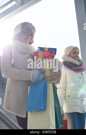 Lächelnde Frauen mit Geschenken und Einkaufstüten durch Fenster im winter Stockfoto