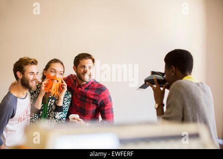 Kreative Geschäftsleute spielerisch posiert für Mitarbeiter mit Sofortbild-Kamera Stockfoto