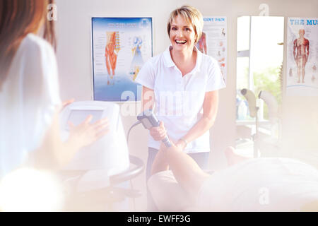 Lächelnd Physiotherapeut mit Ultraschallsonde am Bein des Patienten Stockfoto