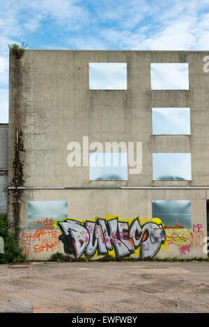 A mit Brettern vernagelt verfallenen Industriegebäude mit Graffiti an den Wänden Stockfoto