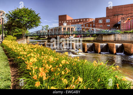 Touristen, überqueren eine Brücke über den Reedy River in spannende und lebendige Innenstadt Greenville, SC. Stockfoto