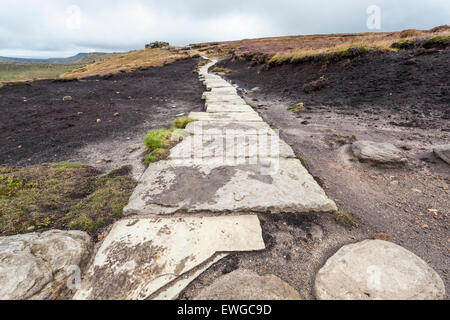 Mauren Erhaltung. Ein Stein Fußweg über stark erodierten Moor auf Kinder Scout in Derbyshire Peak District National Park, England, Großbritannien Stockfoto