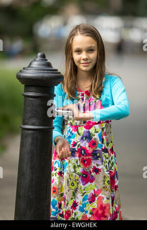 Kleine süße Mädchen wäscht Hände unter Wasser Handpumpe auf der Straße in der Altstadt. Stockfoto