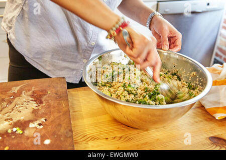 Person, Couscous-Salat in einer Schüssel mischen Stockfoto