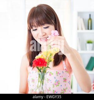Glückliche asiatische Hausfrau mit Schürze Blumen Vase arrangieren. Junge Frau, die Zuhause Leben Lifestyle zu Hause. Stockfoto