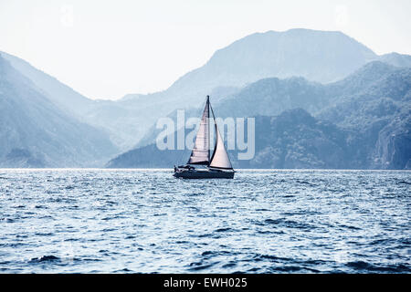 Wunderschöne Landschaft, Kreuzfahrt Segelboot segeln auf den Abstand auf Hintergrund große majestätische Berge, romantische im Meer Stockfoto