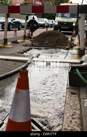 Gebrochenen / platzen Wasserleitung Rohr undicht kann Wasser austreten und entstehen durch die Straße & fließen in die Gosse in / Straße. UK Stockfoto