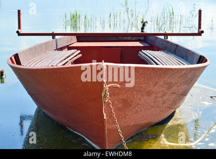 Kleine rote Ruderboot am Ufer des See mit Schilf im Hintergrund Stockfoto