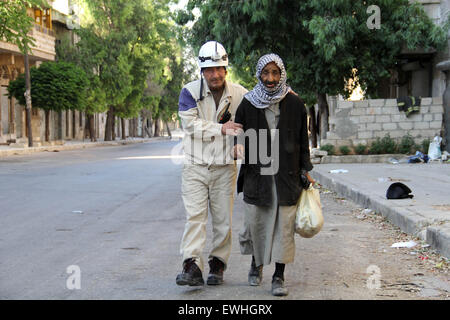 Aleppo, Aleppo, syrische arabische Republik. 24. Juni 2015. Mohammed Mashadi, ein Mitglied des 40-Jahr-alten syrischen Zivilschutz hilft einen älteren Mann eine Straße in Bab al-Nairab-Distrikt in der nördlichen syrischen Aleppo, 26. Juni 2015 überqueren. Einige 600 Syrer, bekannt als '' Weißhelme '' oder syrischen Zivilschutz Einheiten sind organisierte freiwillige, die als Rettung Mitglieder handeln, arbeiten ohne Rücksicht auf Sekte oder Religion in Bereichen wie Aleppo und Idlib Provinzen im Nordwesten des Landes. In den letzten sechs Monaten haben sie mehr als 2.500 Menschenleben gerettet aufgenommen. Sie laufen nach dem Lauf Bomben gesunken und Thro Graben Stockfoto