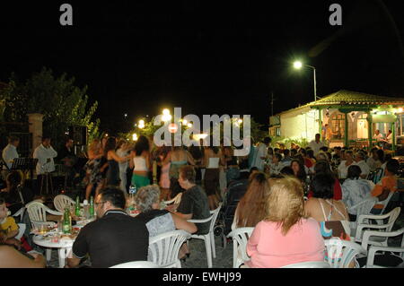 Touristen, die miteinander selbst tanzen griechische Volkstänze in Thanos Dorfplatz Lemnos (Limnos) Insel Nachtleben zu genießen. Stockfoto