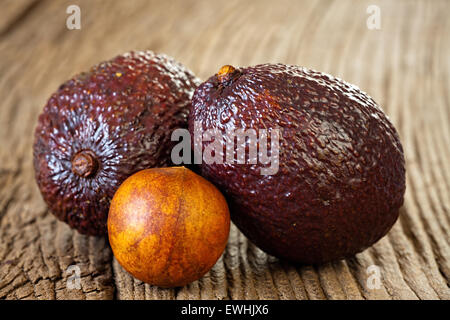 Nahaufnahme von zwei Reife Avocados und Avocado Stein auf einem alten rustikalen Holzbrett Stockfoto