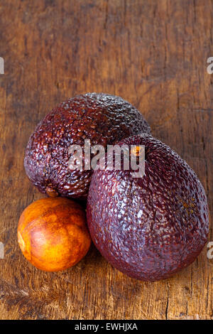 Nahaufnahme von zwei Reife Avocados und Avocado Stein auf einem alten rustikalen Holzbrett Stockfoto