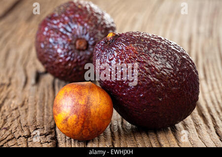 Nahaufnahme von zwei Reife Avocados und Avocado Stein auf einem alten rustikalen Holzbrett Stockfoto