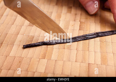 Schneiden die Vanilleschote mit einem Messer auf Bambus Schneidbrett geöffnet Stockfoto
