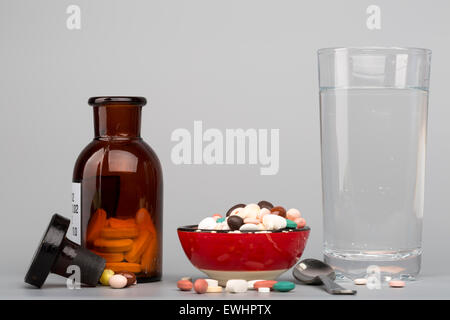 Verschiedenen farbige Pillen, medizinische Flasche eine Glas Wasser Stockfoto