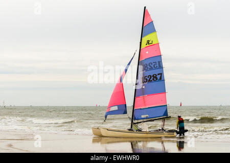 Eine Frau Strände ihr Katamaran am Strand. Stockfoto