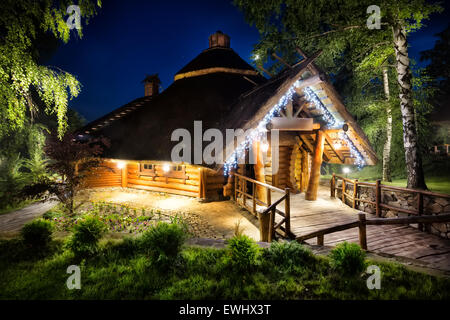 Märchenhafte Holzhaus beleuchtet Lichter unter dem Nachthimmel Stockfoto