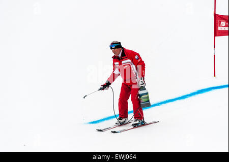 Ein Kurs Marschall Markierung der Ski-Piste mit blauen Farbstoff vor einem Riesenslalom-Rennen. Ein Rennen Tor im Hintergrund. Stockfoto