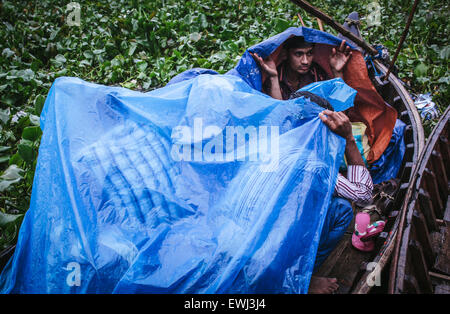 Dhaka, Bangladesch. 26. Juni 2015. Menschen, die sich vor Regen mit Polyethylen-Platten in einem Boot auf dem Fluss Buriganga zu schützen. Monsun-Regen beginnt in Bangladesch von Juni bis Oktober. © Belal Hossain Rana/Pacific Press/Alamy Live-Nachrichten Stockfoto